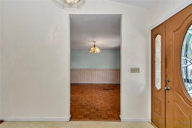 foyer featuring a chandelier and wainscoting