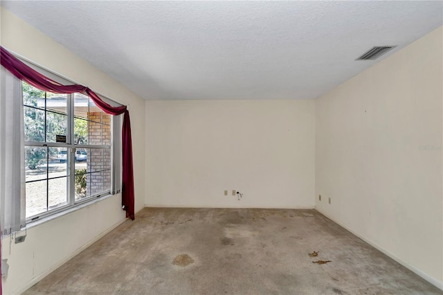 unfurnished room with a textured ceiling, light colored carpet, and visible vents