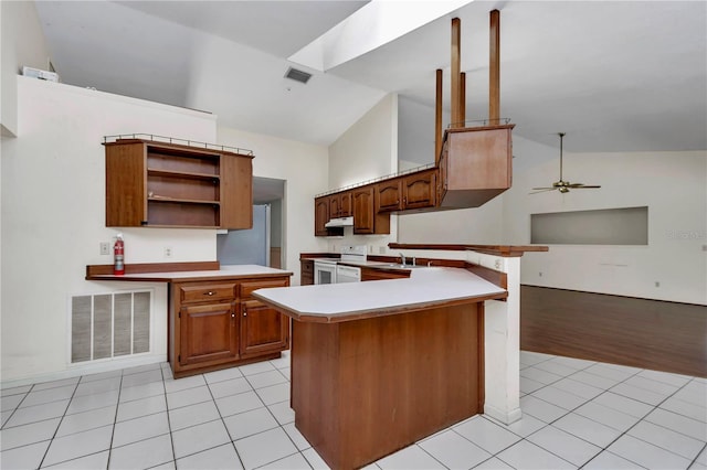 kitchen with a peninsula, white electric stove, under cabinet range hood, and visible vents