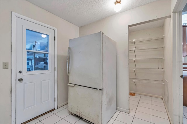 clothes washing area with light tile patterned floors, baseboards, and a textured ceiling