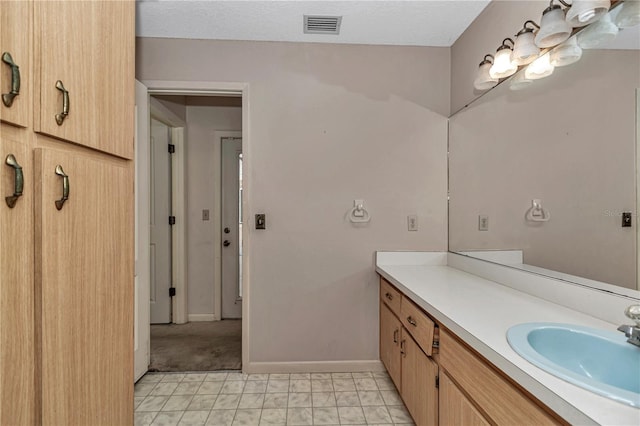 bathroom with vanity, a textured ceiling, baseboards, and visible vents