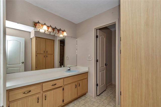 bathroom with baseboards, a textured ceiling, and vanity