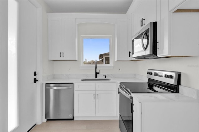 4405 Rockledge Rd, Orlando, FL 32807 - kitchen featuring white cabinetry, a sink, stainless steel appliances, and light stone counters