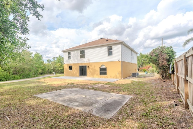 back of house with central air condition unit, a patio area, a lawn, and fence
