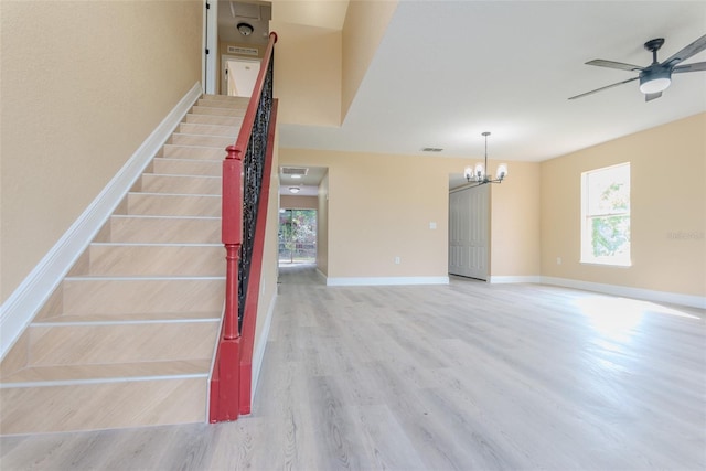stairs with ceiling fan with notable chandelier, baseboards, wood finished floors, and visible vents