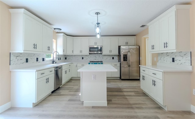 kitchen with a center island, a sink, stainless steel appliances, backsplash, and white cabinetry