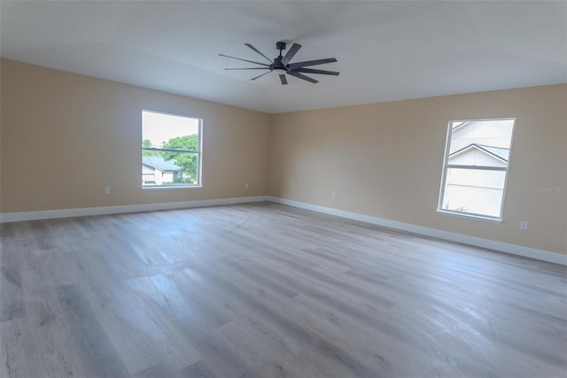 unfurnished room with wood finished floors, a ceiling fan, and baseboards