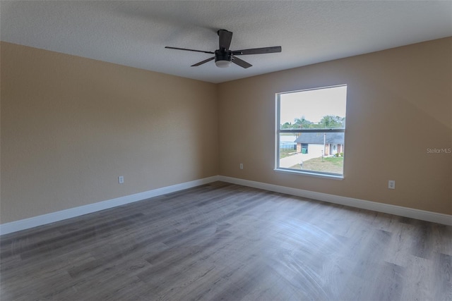 empty room with ceiling fan, baseboards, wood finished floors, and a textured ceiling
