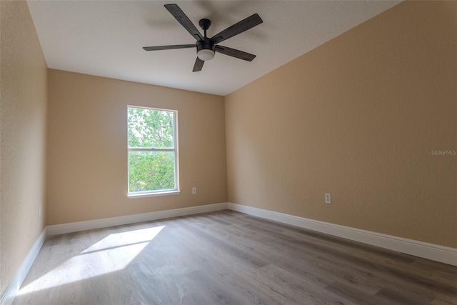 unfurnished room featuring baseboards, wood finished floors, and ceiling fan