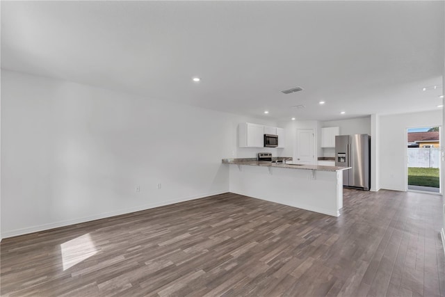 1032 Cannock Dr, Kissimmee, FL 34758 - kitchen with white cabinetry, stainless steel appliances, dark wood-style floors, visible vents, and a peninsula