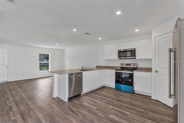 1032 Cannock Dr, Kissimmee, FL 34758 - kitchen featuring a peninsula, stainless steel appliances, recessed lighting, dark wood-type flooring, and white cabinetry