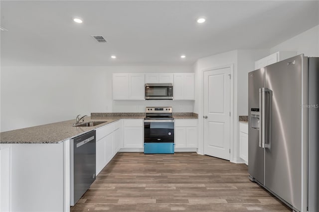 1032 Cannock Dr, Kissimmee, FL 34758 - kitchen with a sink, wood finished floors, dark stone countertops, stainless steel appliances, and white cabinets