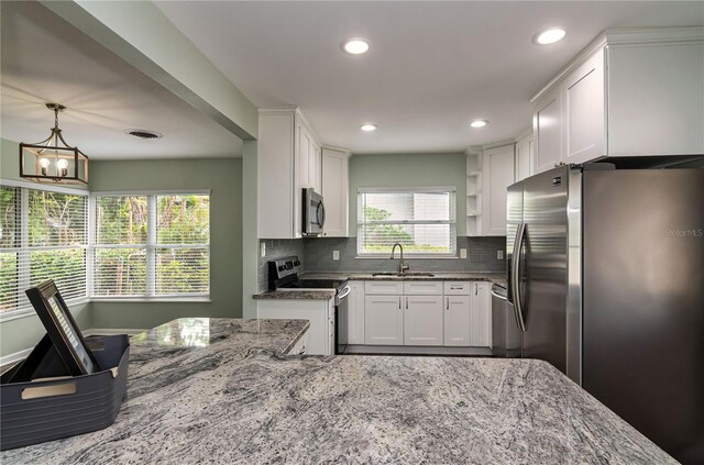 kitchen featuring light stone countertops, white cabinets, a sink, and stainless steel appliances