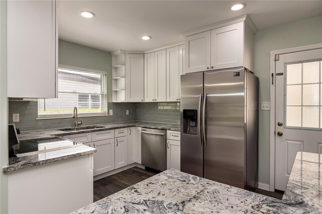 kitchen featuring light stone countertops, white cabinets, a sink, and stainless steel appliances