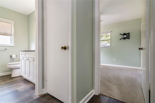 bathroom with baseboards, wood finished floors, toilet, and vanity