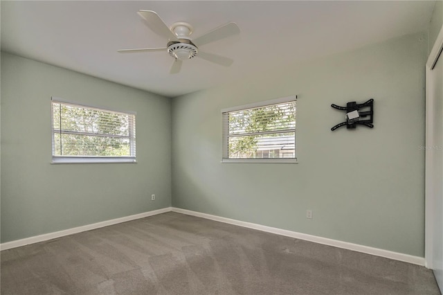 carpeted spare room with baseboards and a ceiling fan