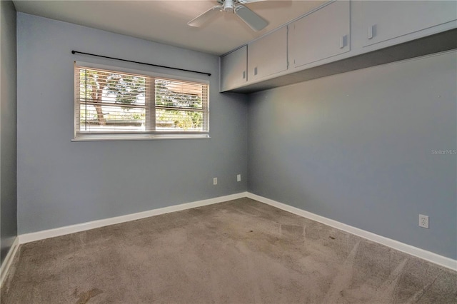 carpeted empty room featuring baseboards and ceiling fan
