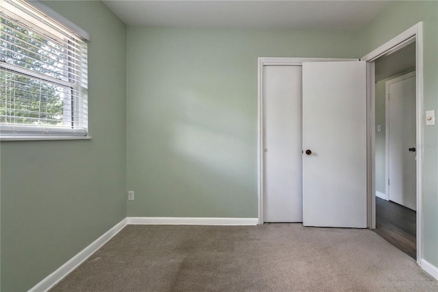 unfurnished bedroom featuring baseboards, carpet flooring, and a closet