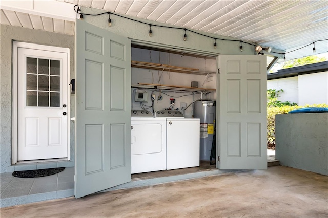 washroom featuring water heater, washing machine and clothes dryer, and laundry area