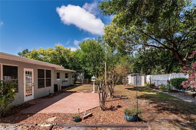 view of yard with an outbuilding, central air condition unit, a fenced backyard, a storage shed, and a patio area
