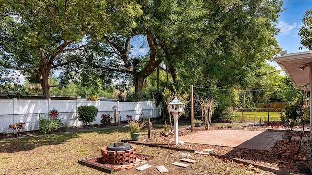 view of yard with an outdoor fire pit, a fenced backyard, and a patio