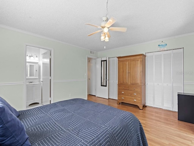 bedroom with light wood-type flooring, a textured ceiling, ornamental molding, connected bathroom, and ceiling fan