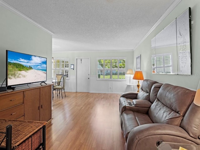 living room with ornamental molding, light wood finished floors, a textured ceiling, and baseboards