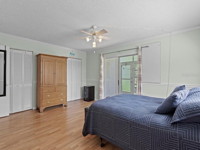 bedroom featuring ornamental molding, light wood-style floors, two closets, a textured ceiling, and a ceiling fan
