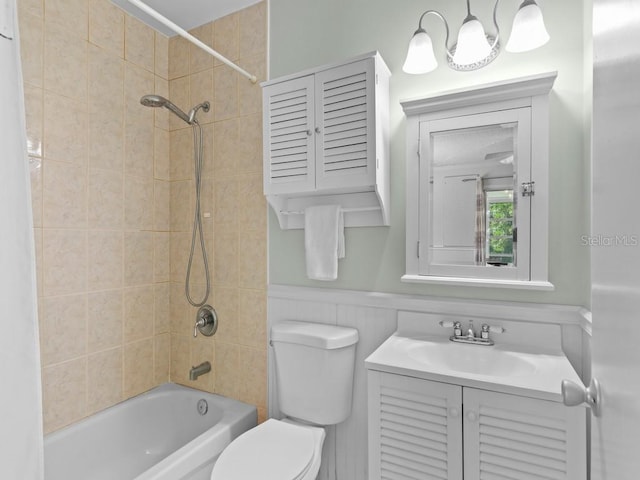 full bath featuring toilet,  shower combination, vanity, and wainscoting