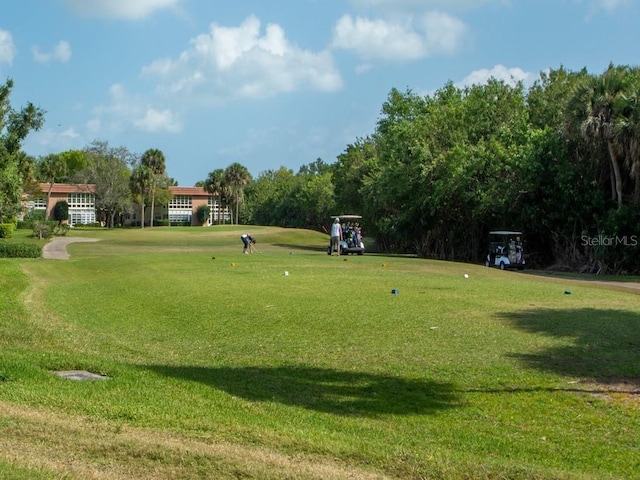 surrounding community with a carport, a yard, and golf course view