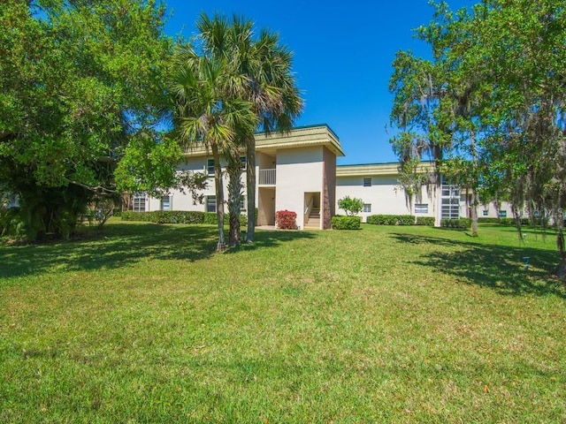 back of property featuring stucco siding, a lawn, and stairway