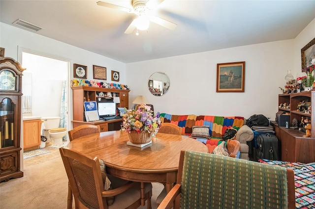 dining room featuring visible vents, a ceiling fan, and light colored carpet