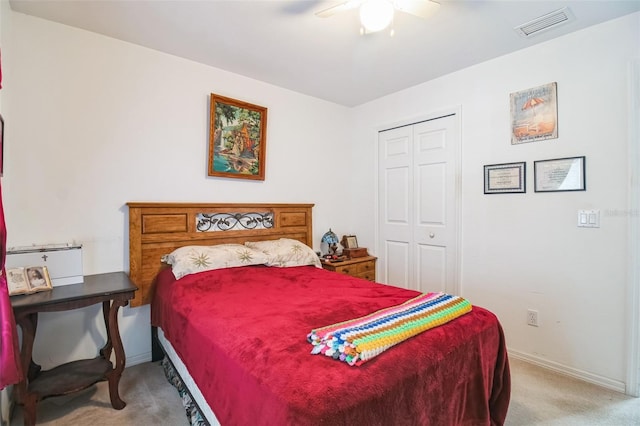 bedroom with a closet, light carpet, baseboards, visible vents, and ceiling fan