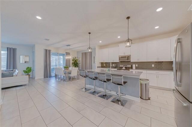 2760 Bookmark Dr, Kissimmee, FL 34746 - kitchen with light countertops, a breakfast bar area, stainless steel appliances, backsplash, and white cabinets