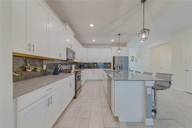 2760 Bookmark Dr, Kissimmee, FL 34746 - kitchen featuring white cabinetry, backsplash, a sink, a kitchen island with sink, and appliances with stainless steel finishes