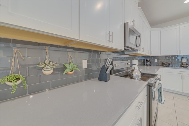 2760 Bookmark Dr, Kissimmee, FL 34746 - kitchen featuring white cabinetry, backsplash, appliances with stainless steel finishes, and light tile patterned floors