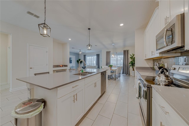 2760 Bookmark Dr, Kissimmee, FL 34746 - kitchen with an island with sink, a sink, backsplash, appliances with stainless steel finishes, and visible vents