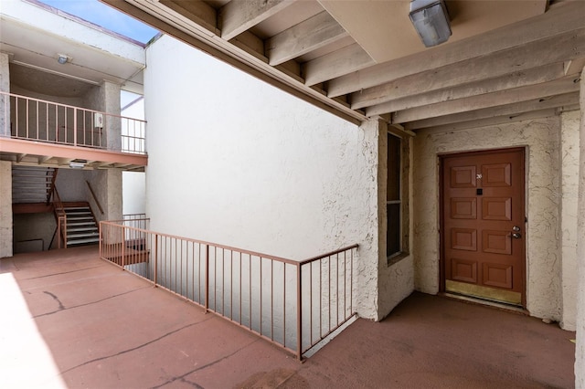 entrance to property featuring a balcony and stucco siding