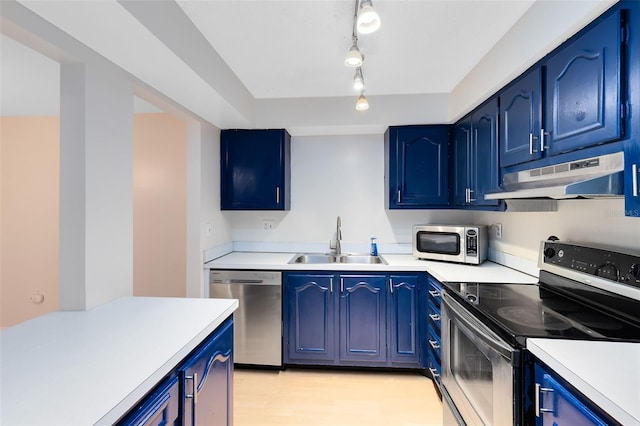 kitchen with blue cabinetry, under cabinet range hood, a sink, and stainless steel appliances