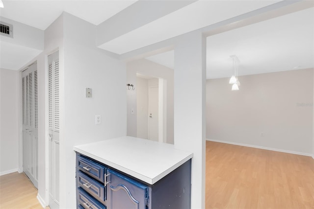 kitchen with light wood finished floors, baseboards, light countertops, and blue cabinets