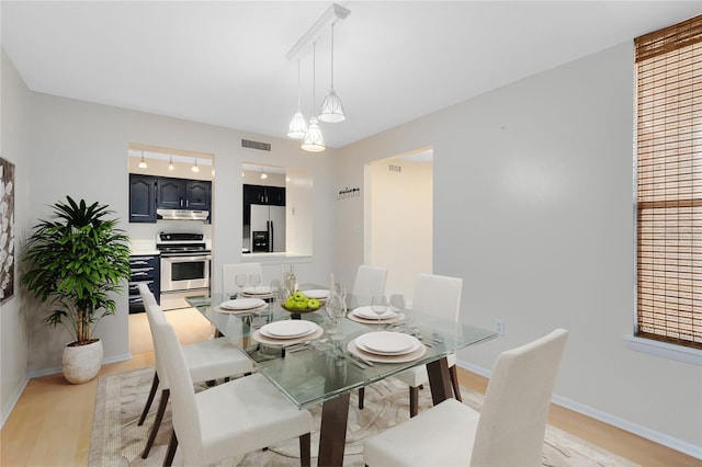 dining space with light wood finished floors, baseboards, and visible vents