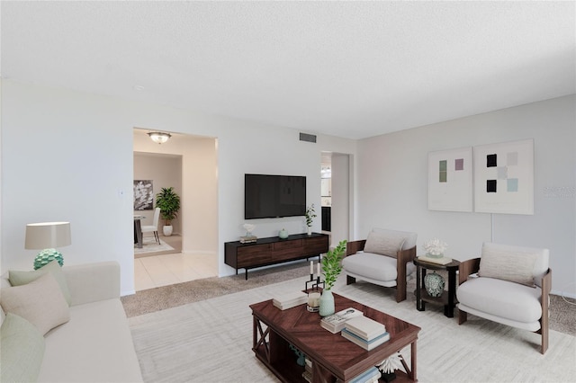 living room with a textured ceiling, visible vents, and light carpet