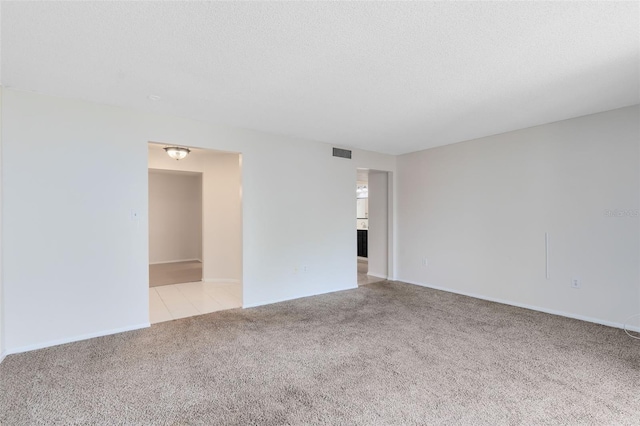 empty room with a textured ceiling, visible vents, and light carpet