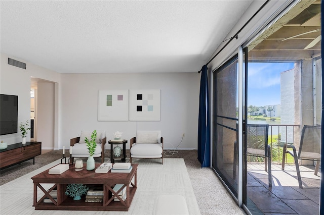 living room featuring visible vents, baseboards, light colored carpet, and a textured ceiling
