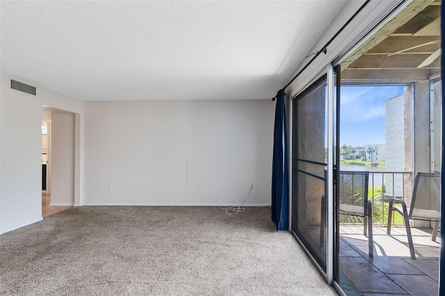 spare room with baseboards, carpet flooring, a textured ceiling, and visible vents
