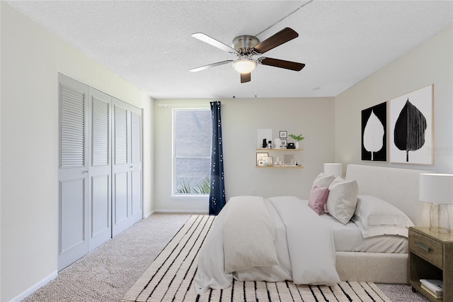 bedroom featuring a closet, a textured ceiling, baseboards, ceiling fan, and carpet
