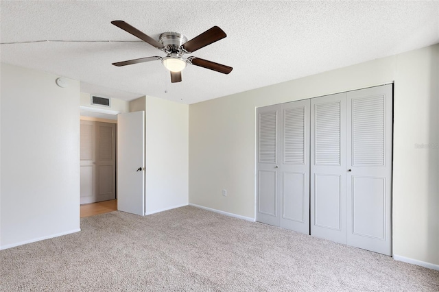 unfurnished bedroom featuring a closet, carpet floors, a ceiling fan, a textured ceiling, and visible vents
