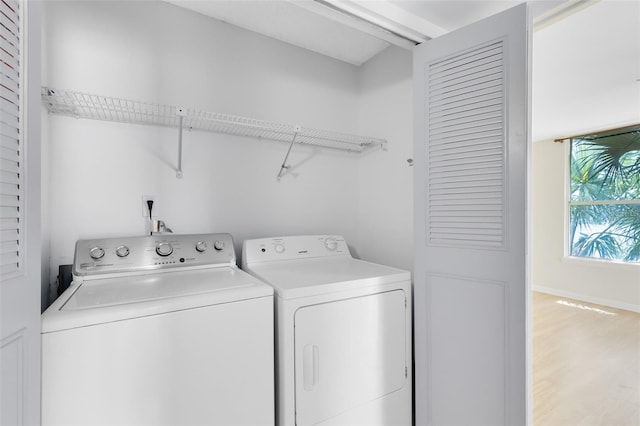 clothes washing area featuring washing machine and clothes dryer, wood finished floors, and laundry area