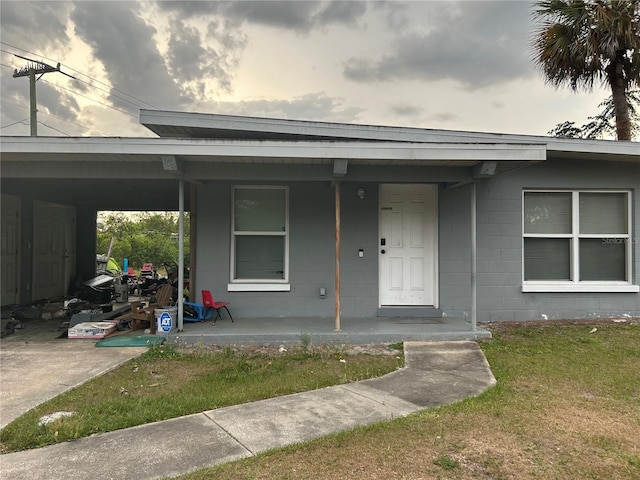 view of front of house featuring concrete block siding, a porch, and a carport