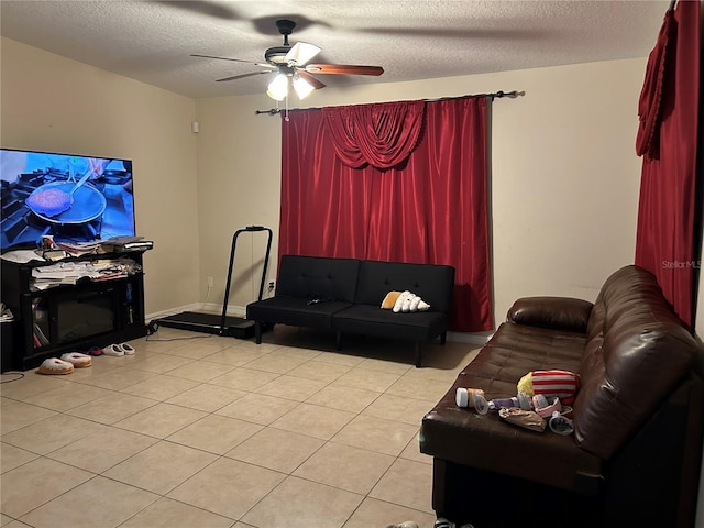 living area featuring a ceiling fan, light tile patterned floors, and a textured ceiling